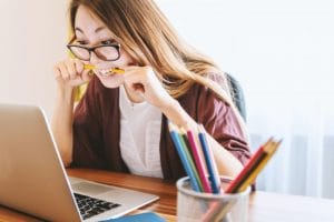 woman biting her pencil because she feels so much stress and anxiety trying to learn how to cope with stress to relieve anxiety