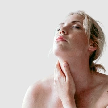 picture of a woman with low energy due to hypothyroidism touching her neck where her thyroid is located