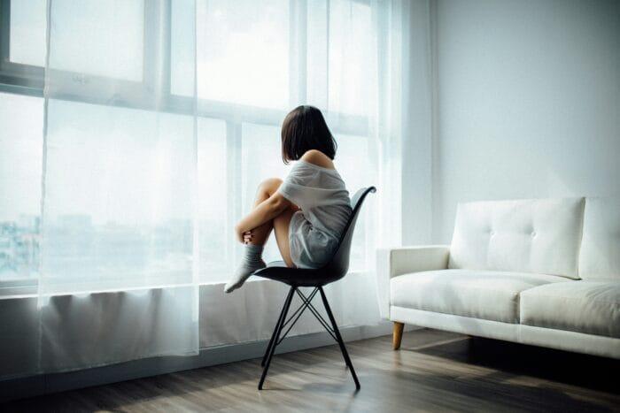 picture of a woman sitting on a chair looking out a window suffering from anxiety and depression due to hormone imbalance wondering how to balance hormones naturally