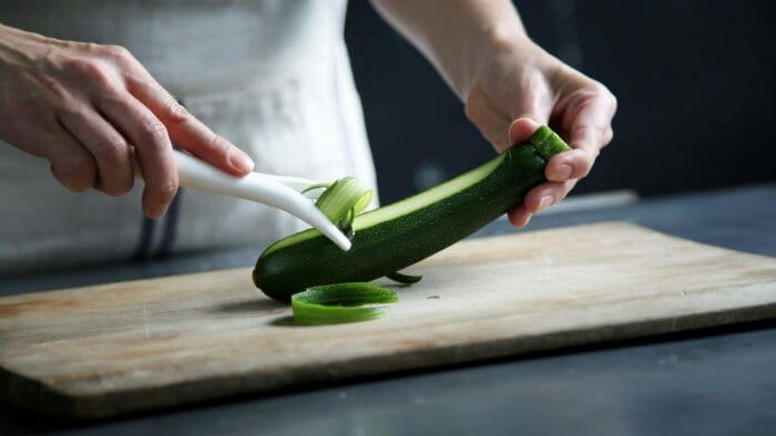 picture of a person making zucchini noodles to make a low carb recipe for a zucchini noodle stir-fry
