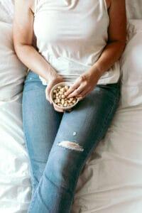 picture of a woman lying on her bed snacking on nuts with mindfulness for weight loss