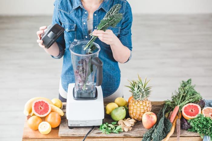 picture of a woman juicing leafy greens in a blender to make a healthy smoothie for weight loss