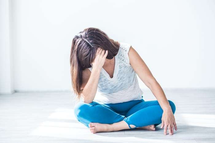 picture of a woman sitting holding her head due to high cortisol from high stress